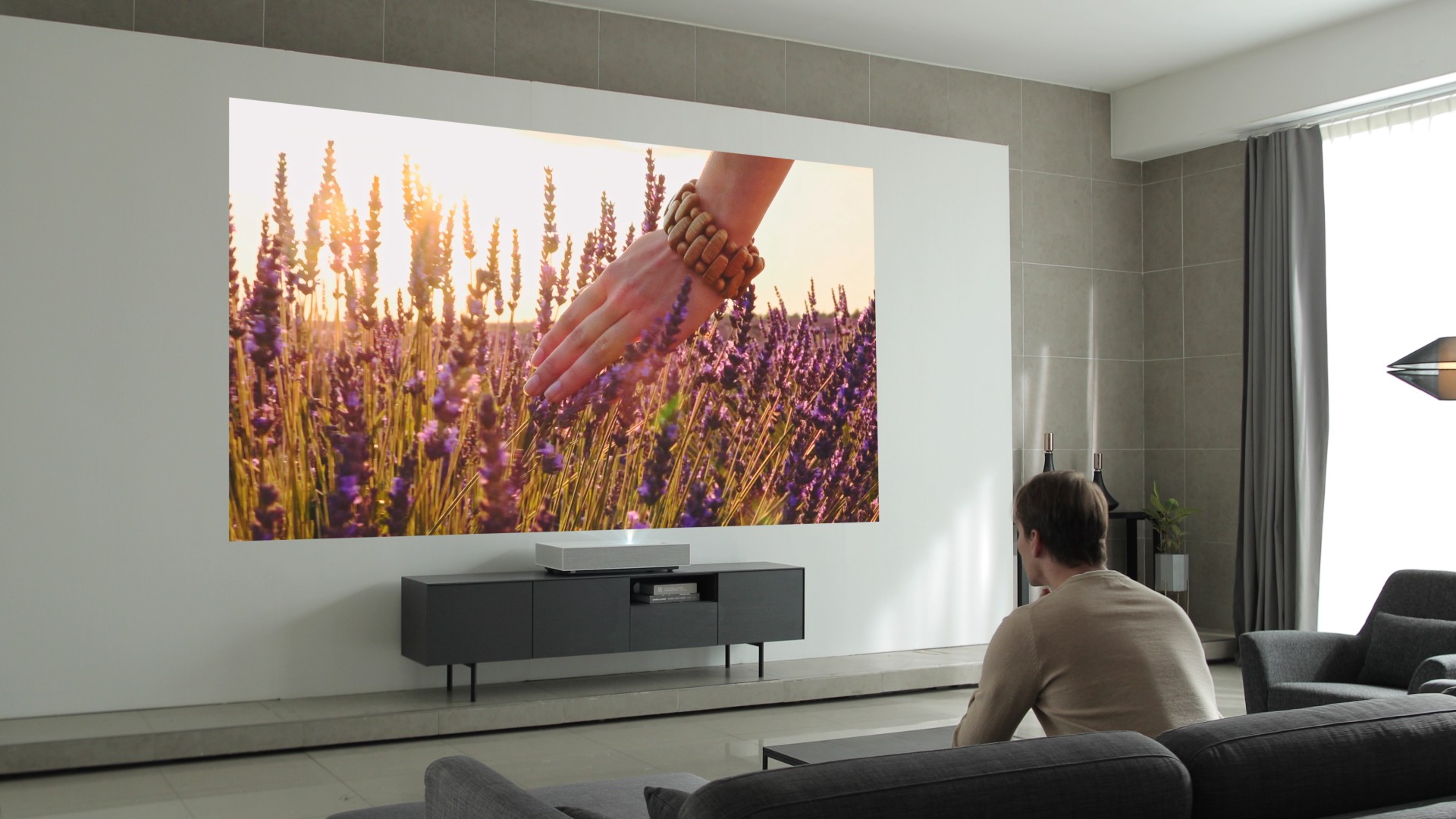 A man is watching a vivid image displayed by the LG CineBeam Laser 4K projector model HU85L