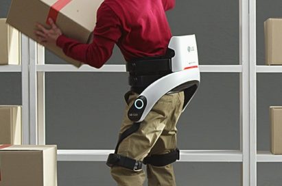 A man lifts a heavy box onto a high shelf while wearing LG CLOi SuitBot