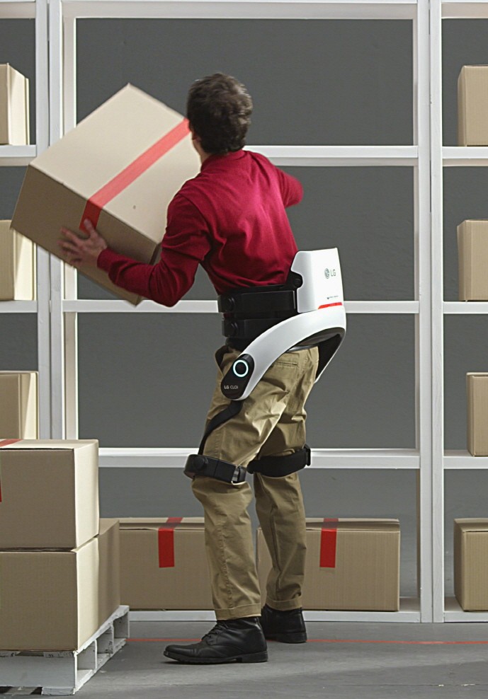 A man lifts a heavy box onto a high shelf while wearing LG CLOi SuitBot