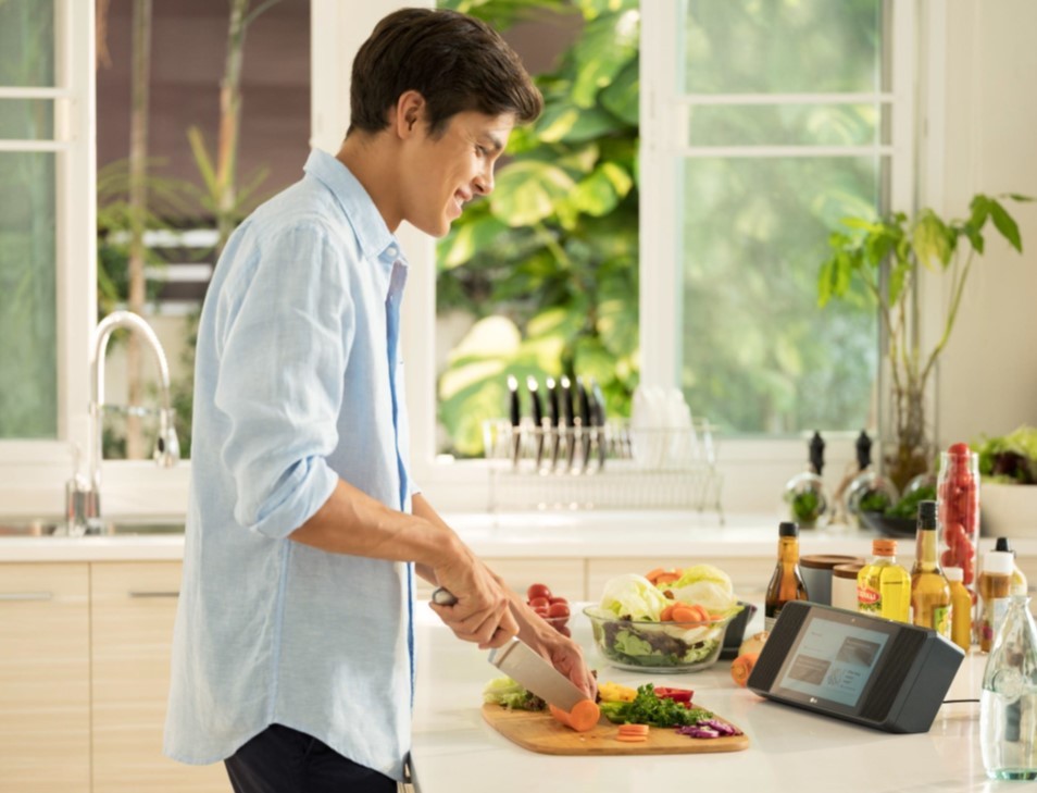 Man slicing vegetables as he looks at a recipe on the LG XBOOM AI ThinQ™ WK9 Smart Display