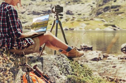 A lady working on pictures with her LG gram while sitting on a rock beside the river