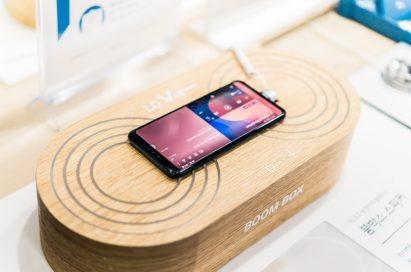 An LG V40 ThinQ is on display at a promotional zone, demonstrating its powerful amplification when placed on a solid surface or box.