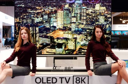 Two female models pose on the promotional stand of LG’s 88-inch 8K OLED TV at LG’s CES booth.