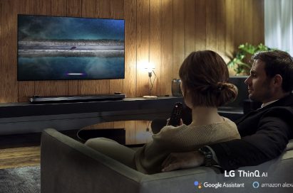 A couple using the LG ThinQ AI TV while sitting on their living room sofa