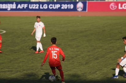 A pitch-side advertisement board displays LG logo in the distance while some soccer players vie for the ball on the ground.