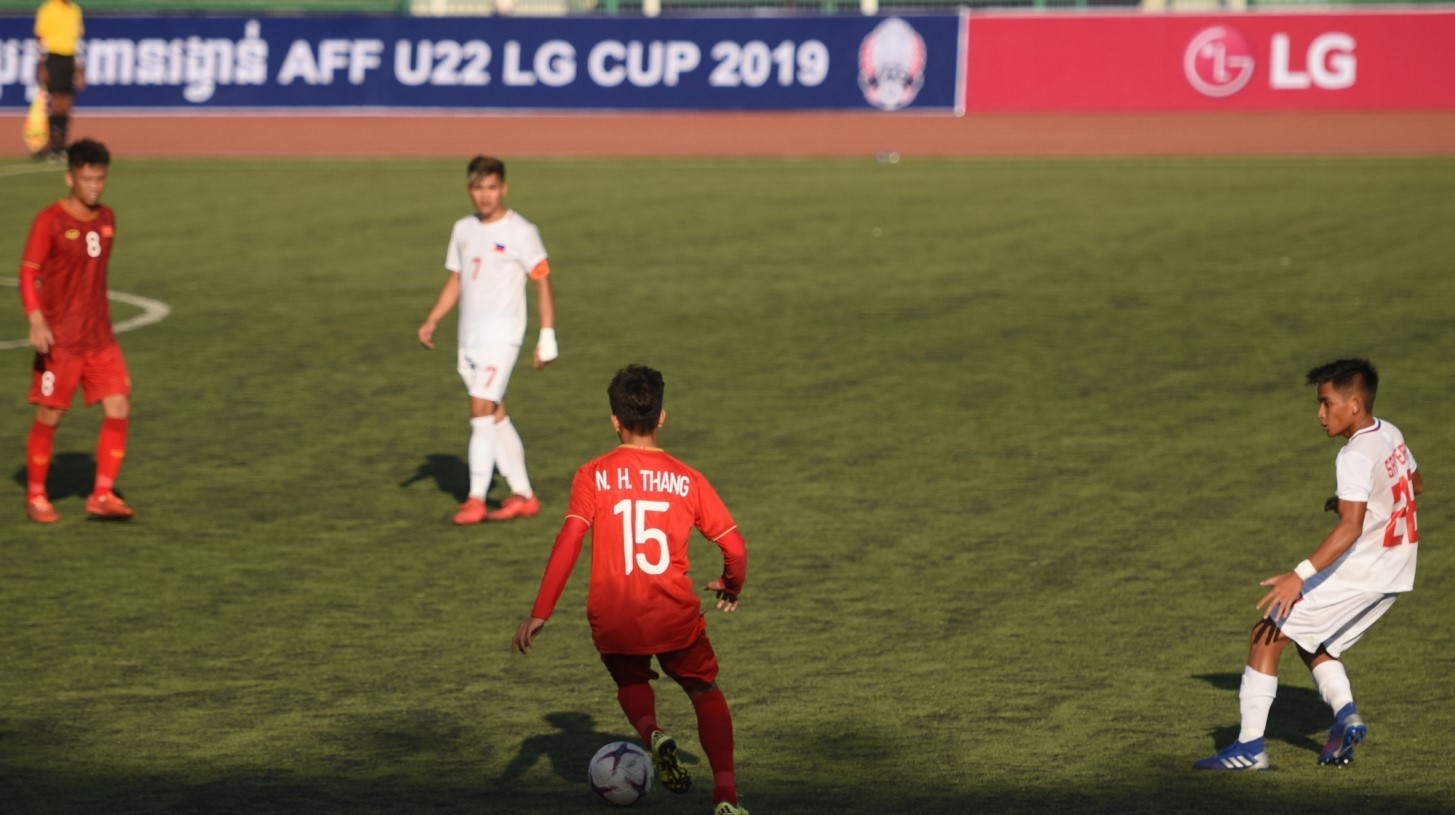 A pitch-side advertisement board displays LG logo in the distance while some soccer players vie for the ball on the ground.