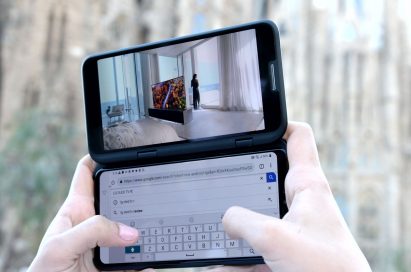 A person holding the LG V50 ThinQ 5G and LG Dual Screen, with the Dual Screen showing a video while the main screen is being used for a Google search