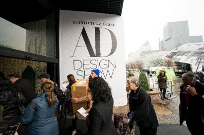 A group of visitors pass by a big logo banner for the 2019 Architectural Digest Design Show in New York City.