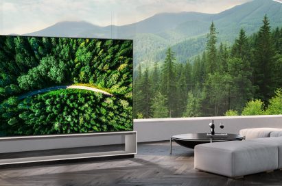 LG 8K OLED TV showing a road in the woods is placed in a spacious room with a spectacular view
