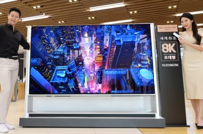 Two models demonstrating LG 8K OLED TV displaying skyscrapers