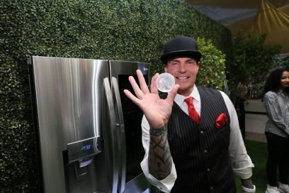 Rapper Vanilla Ice holds up a round LG Craft Ice ball in front of LG InstaView™ Door-in-Door® Refrigerators with Craft Ice.