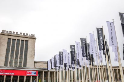 Partial view of Messegelände Berlin ExpoCenter City with promotional flags of the LG SIGNATURE brand and its brand theme “The Art of Essence” flying in front