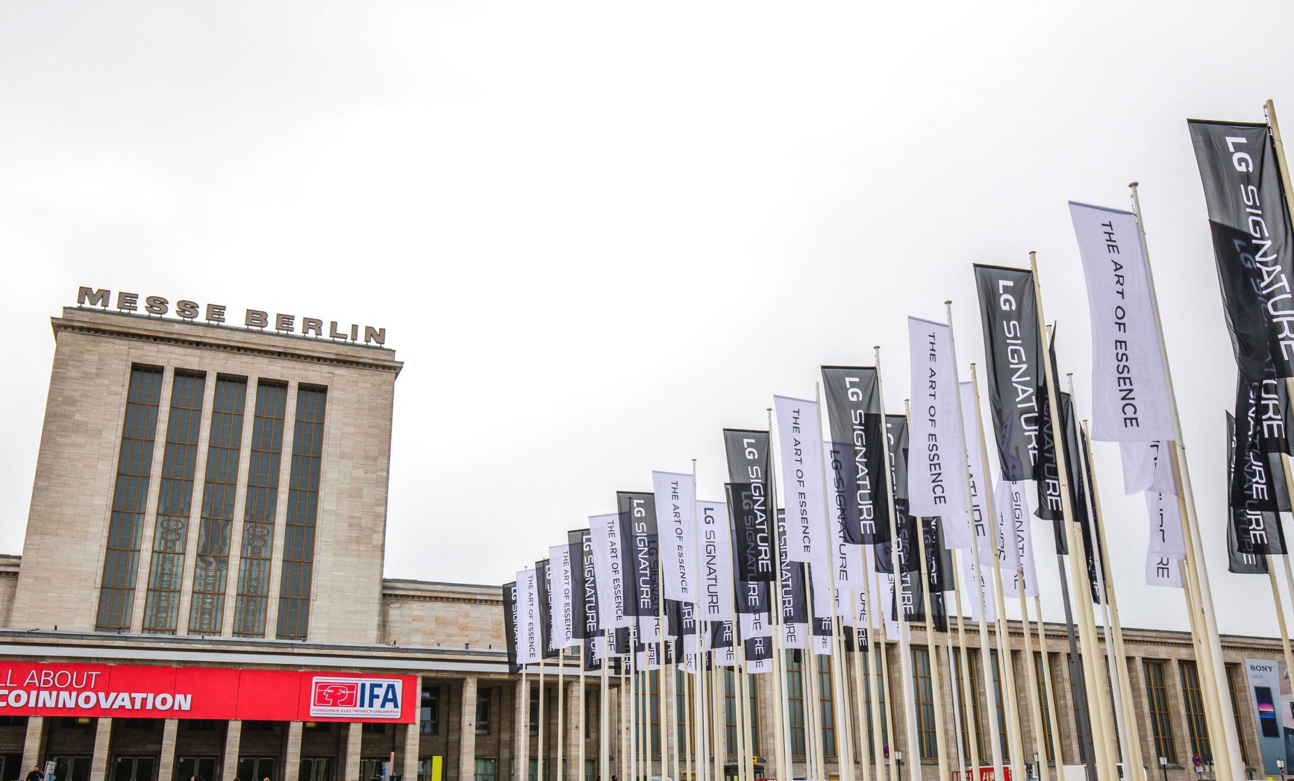 Partial view of Messegelände Berlin ExpoCenter City with promotional flags of the LG SIGNATURE brand and its brand theme “The Art of Essence” flying in front
