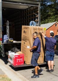 Two volunteers unload LG-donated home appliances from the container of a truck.