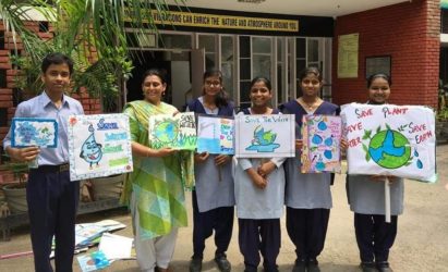 Standing next to a teacher, five students hold up their paintings with some catch phrases to encourage water conservation.