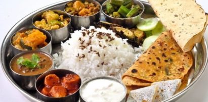 A round metal dish full of Indian food