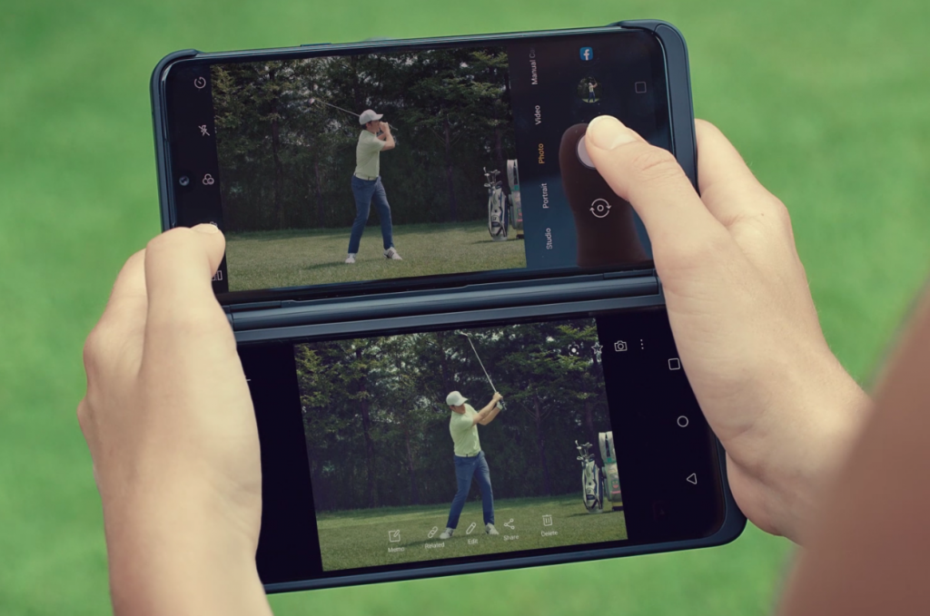 A man holds LG G8XThinQ with LG Dual Screen in her two hands horizontally to watch the golf swing video on the golf course.