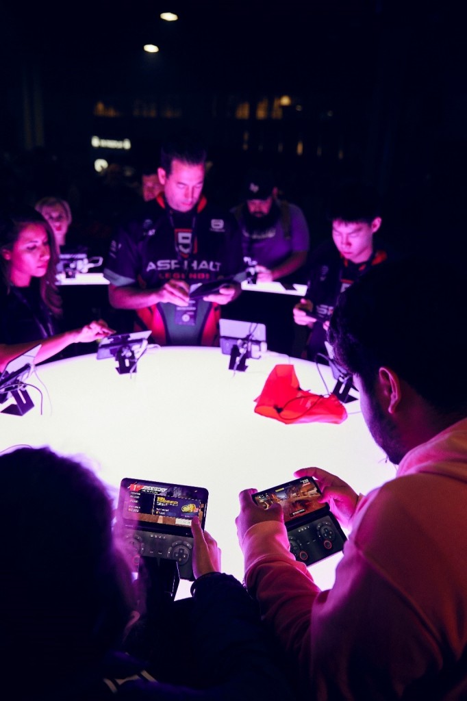 Gamers test out the gameplay on LG G8X ThinQ with Dual Screen around an illuminating round table.