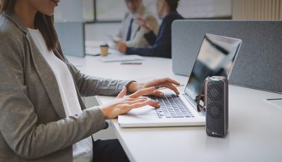 Woman is using laptop on the table and LG PuriCare Mini is standing next to her laptop