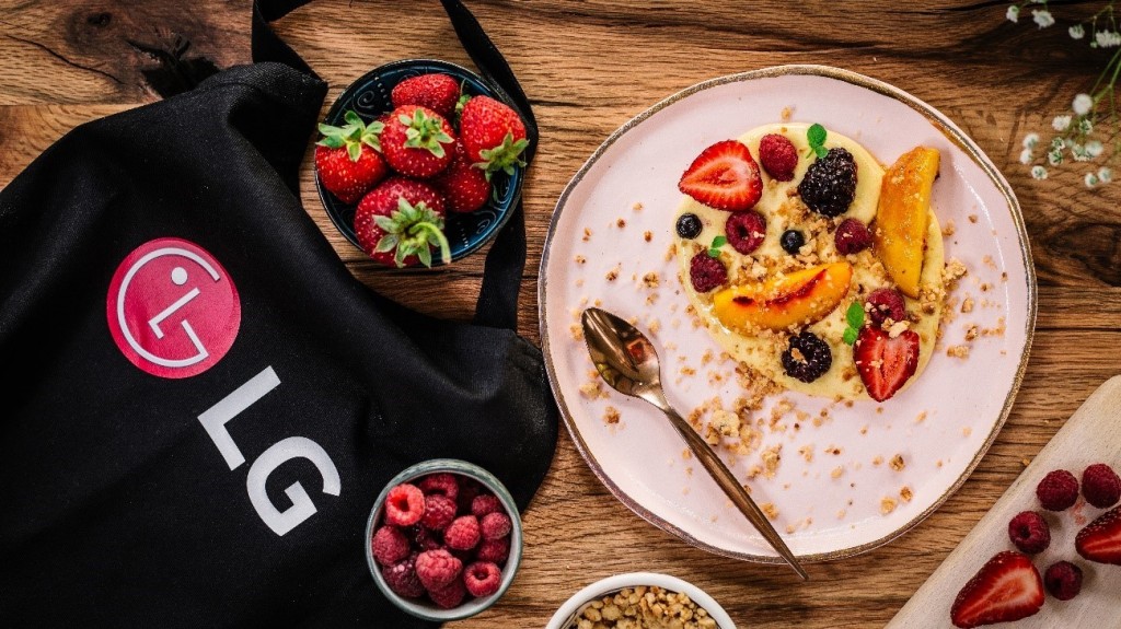 A promotional image showing an LG bag surrounded by plates and bowls of healthy natural foods including strawberries and raspberries.