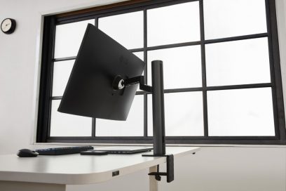 Rear side view of the LG UltraFine monitor 32UN880 with its clamp tightly holding the edge of the desk