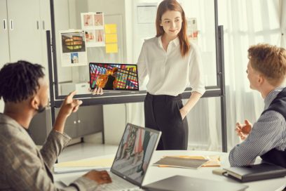 Three colleagues discussing a colorful picture on LG gram model 14T90N as it’s held effortlessly in one hand by one of them