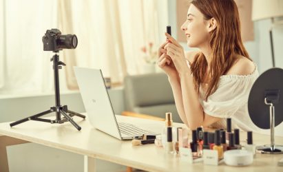 A female video creator demonstrating how to apply makeup via a camera and her LG gram model 17Z90N on the desk in front.