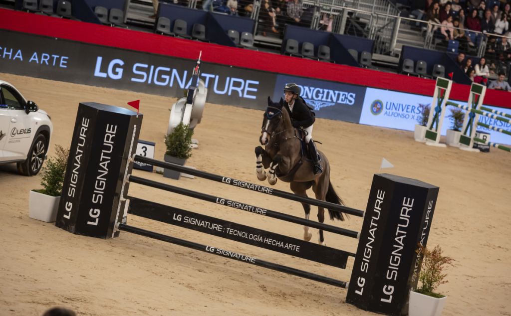 A rider and her horse leap over a tall hurdle at an equestrian competition while the jump displays the LG SIGNATURE logo to highlight the brand as the main sponsor.