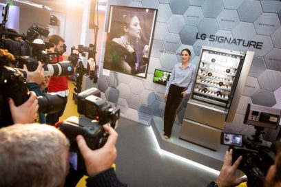 Fashion designer Tamara Falcó poses next to LG SIGNATURE Wine Cellar and her movie-inspired artwork as numerous reporters take photos.