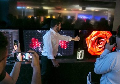 LG's Pedro Valery compares the picture quality of the LG OLED TV with that of products from other brands at Lab Tech LG, as reporters record videos and take pictures.