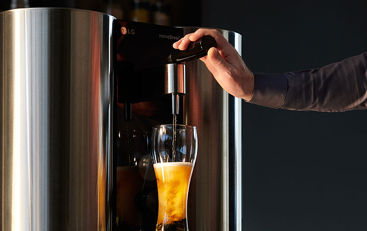 A man holds down the tap of LG HomeBrew to pour the perfect beer