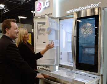 A man and woman take a closer look at the technology found inside the LG InstaView Door-in-Door refrigerator by opening its fridge door compartment