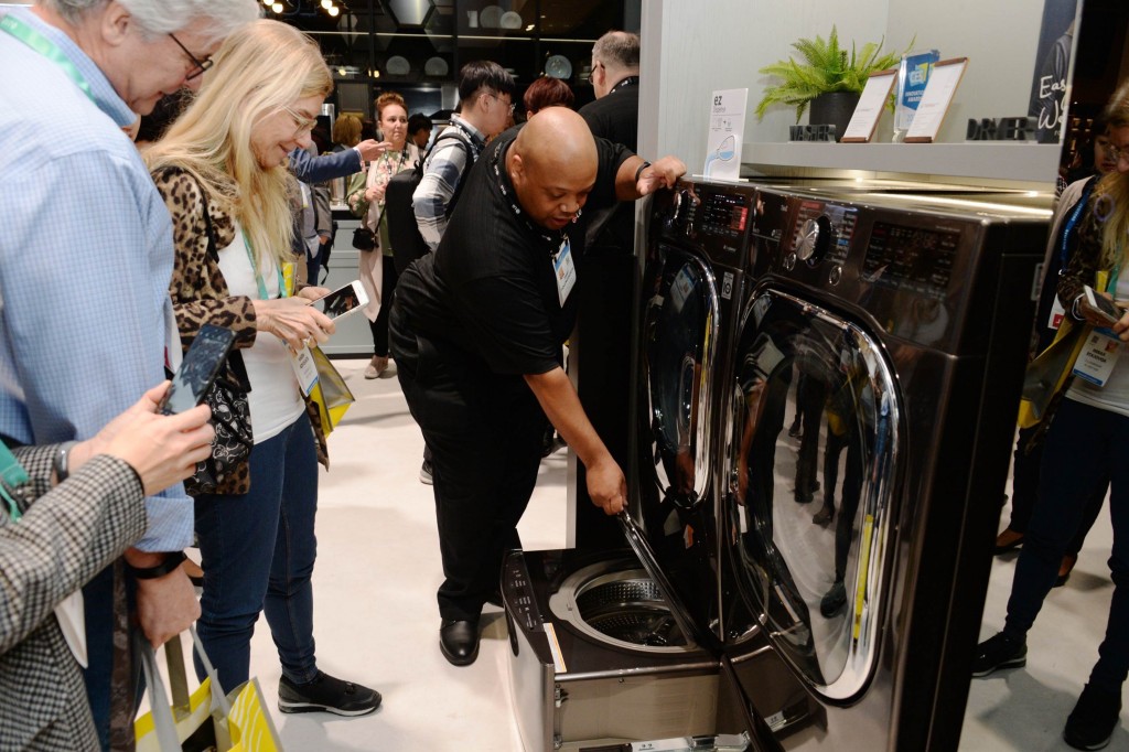 An LG representative demonstrates the second drum of an LG TwinWash appliance to onlookers at CES 2020