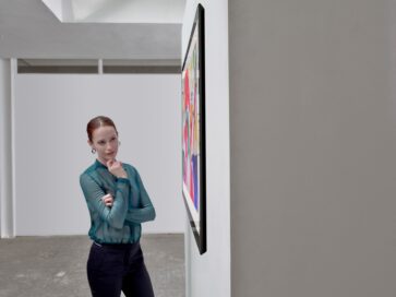 A woman admiring LG’s art-inspired Gallery series model GX as it hangs flush on the wall of a gallery thanks to its ultra-thin form factor