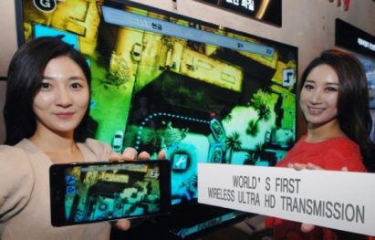 Two women hold up an LG phone and banner highlighting the world’s first wireless Ultra HD Transmission technology