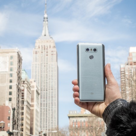 A person holds up the LG G6 to show its rear side with the Empire State Building in the background