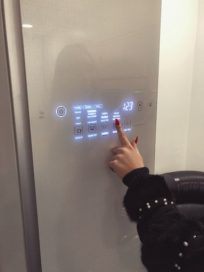 A woman pushes a button on the front door display panel of the LG Styler to set it to cleaning mode