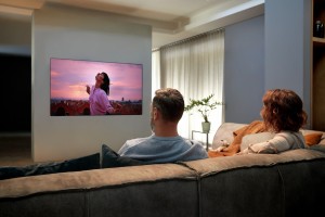 A man and a woman enjoying the state-of-the-art picture quality that comes with LG OLED TV GX on their cozy living room sofa