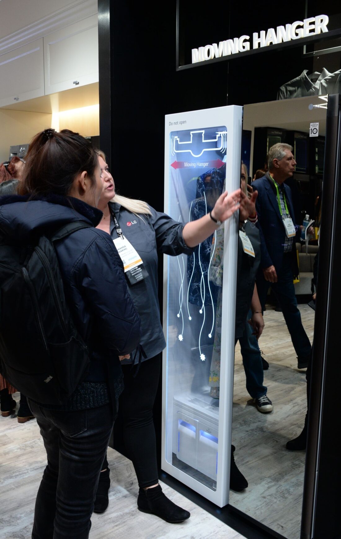 Two women look at and try out a display of LG’s Moving Hanger technology at the LG Styler display zone.