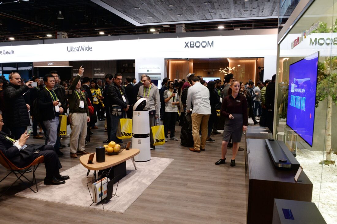 CES attendees walk around the LG HE display zone, looking at an LG SIGNATURE OLED TV W on the wall.