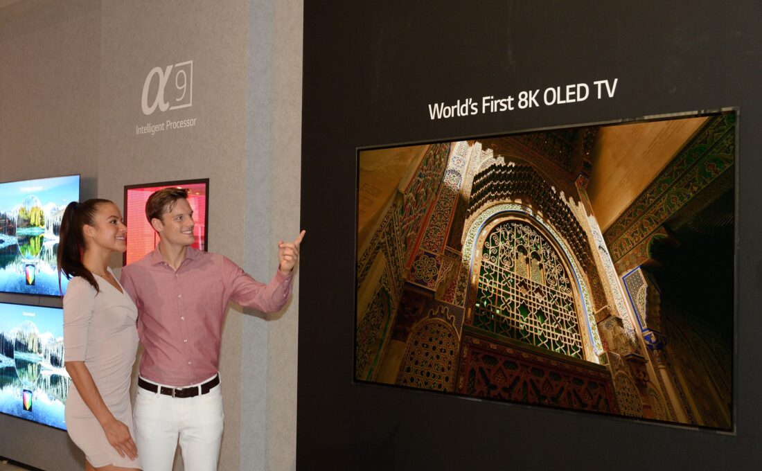 Another view of the World’s First 8K OLED TV with A9 Intelligent Processor display at IFA 2018, with a male and female model standing on the side pointing to the screen