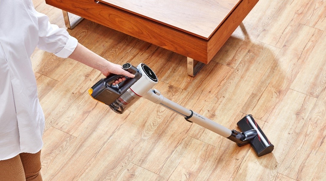 A woman uses the LG CordZero A9 vacuum cleaner to clean the wooden floor
