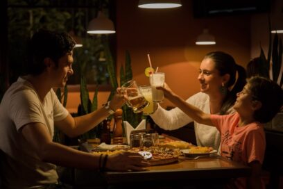 A family ‘cheers’ as they eat around the dinner table under dim lighting