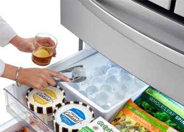 A woman takes an ice ball from the LG refrigerator’s Craft Ice Maker to chill her drink