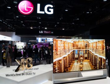 Front view of an LG 8K OLED TV set positioned on the right side of a promotional sign saying 