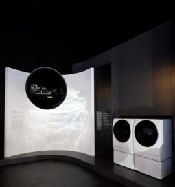 View of a pair of the LG SIGNATURE washer-dryers and a display to the left giving information about their features.