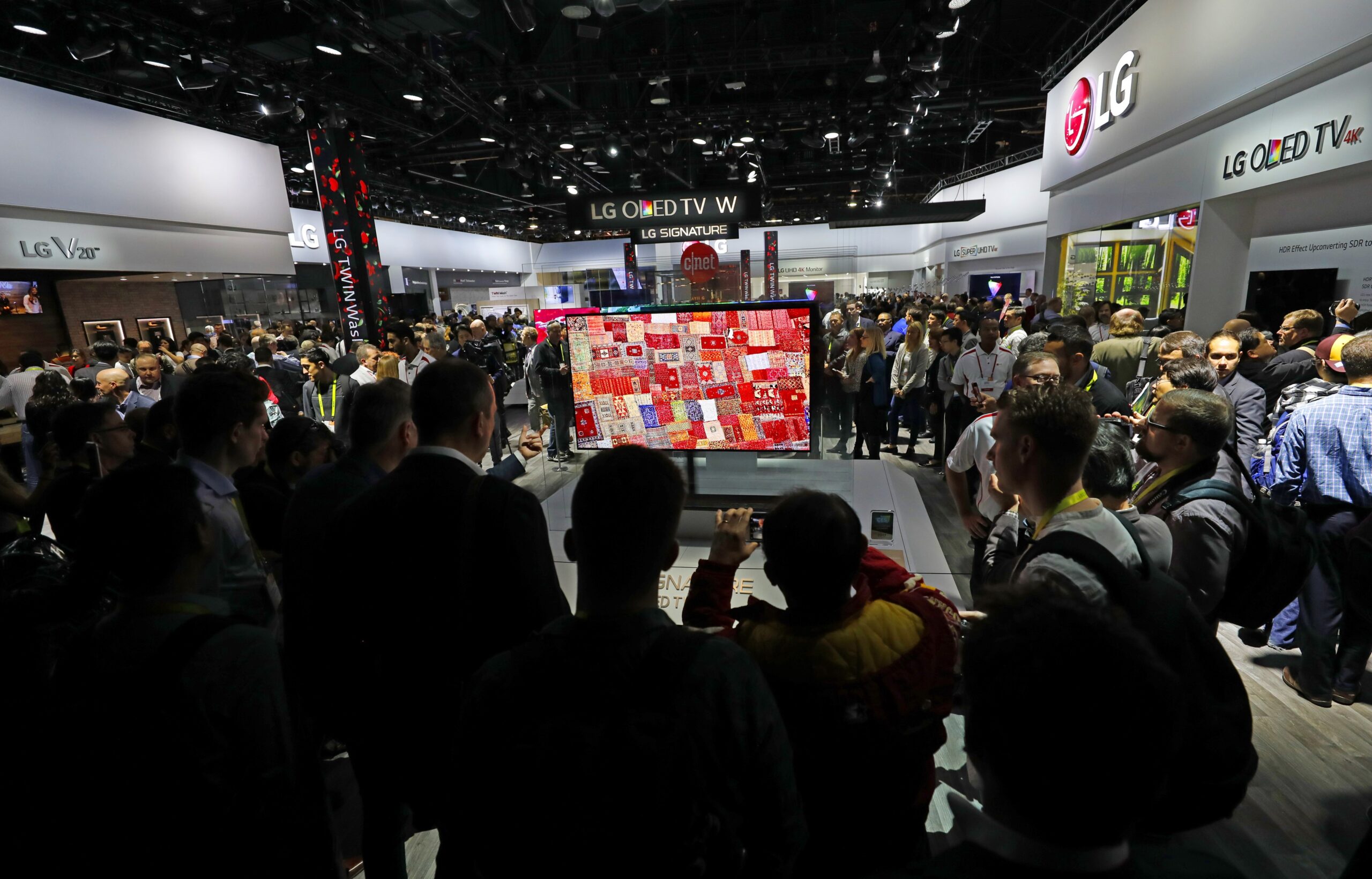 A drove of attendees and reporters at CES 2017 look at the screen of the LG SIGNATURE OLED TV W at LG's booth.