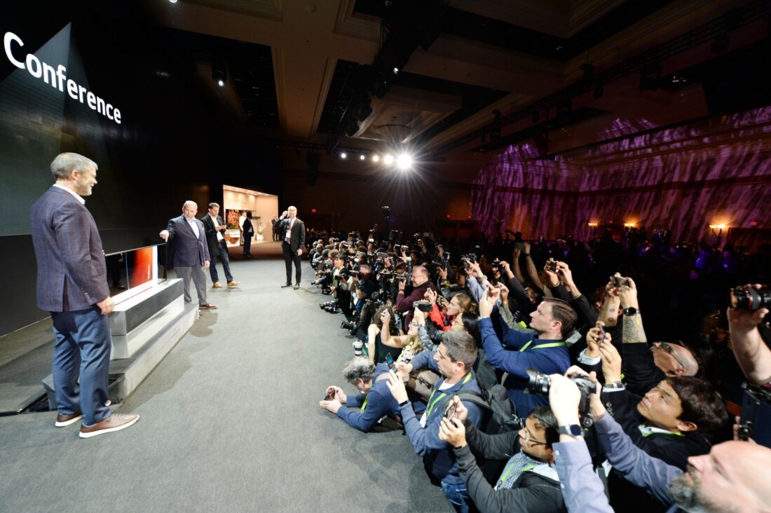 David VanderWall, Senior Vice President of Marketing at LG Electronics USA and Tim Alessi Senior Director of Product Marketing for Home Entertainment Products at LG Electronics USA are onstage discussing the LG SIGNATURE OLED TV R at LG's CES 2019 Press Conference while a number of reporters take pictures of the TV.