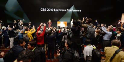 Far shot of the CES 2019 LG Press Conference with a pair of male and female models onstage posing while reporters are recording and taking pictures