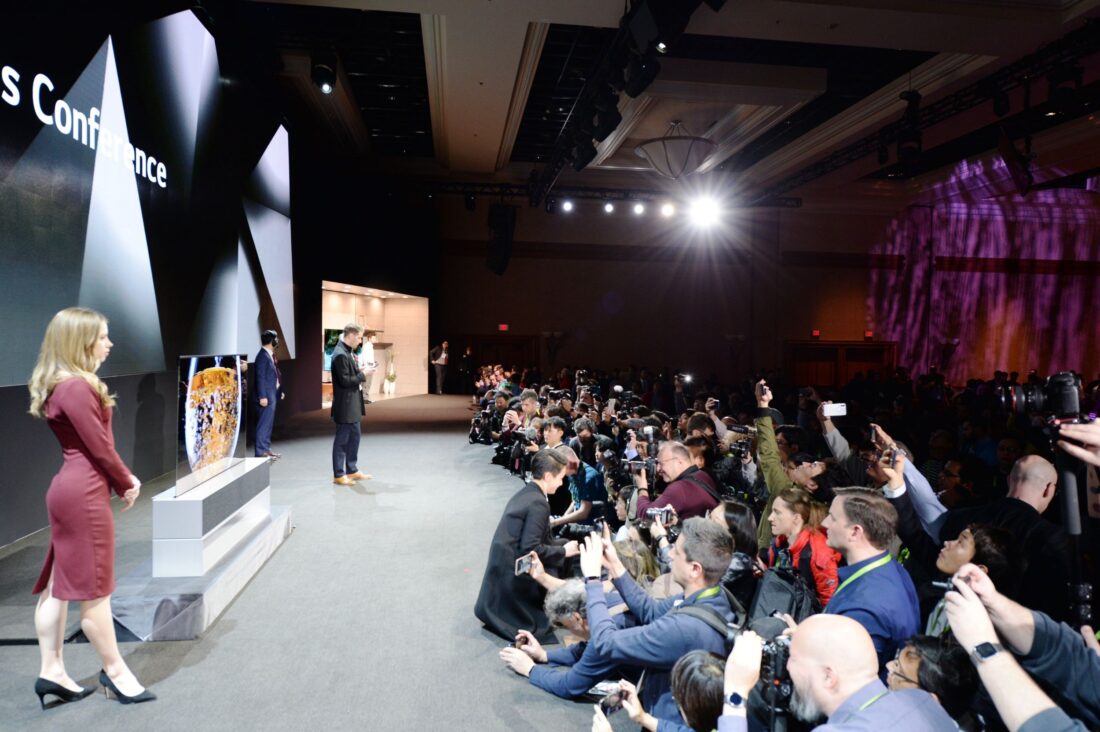 Side view of the CES 2019 LG Press Conference with a pair of male and female models onstage posing while reporters are recording and taking pictures